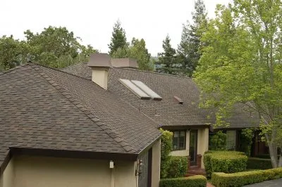 A well-maintained house in Burlingame featuring a new roof installed by Mid-Peninsula Roofing Inc., surrounded by greenery and trees.